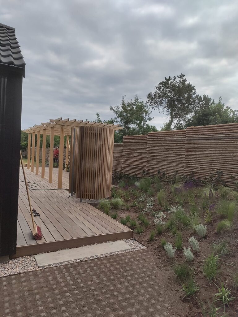 Træterrasse med pergola og nyplantet græsbed